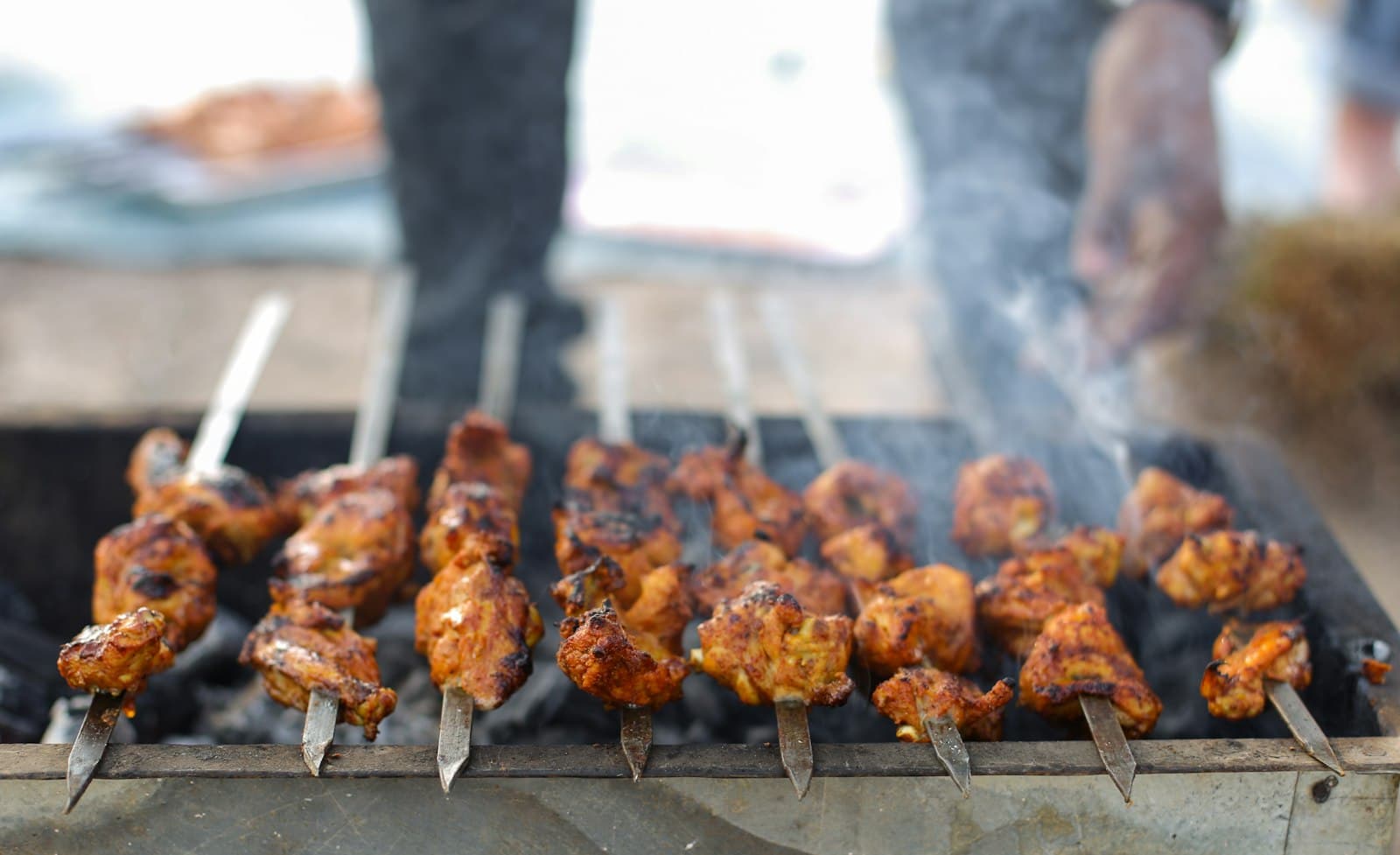 Chicken tikka skewers cooking over live coals